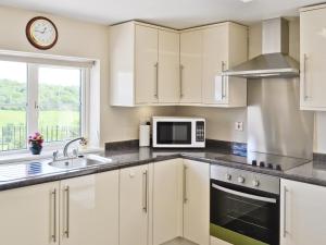 a kitchen with white cabinets and a sink and a microwave at Thornhill in Whitchurch