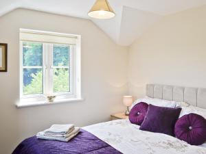 a bedroom with a bed with purple pillows and a window at Thornhill in Whitchurch