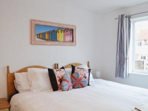 1 cama con 2 almohadas y una foto en la pared en Coastal Hideout, en Wells-next-the-Sea