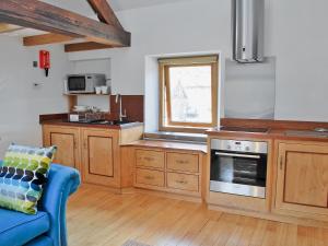 a kitchen with wooden cabinets and a blue couch at Carringtons Barn in Edale