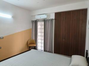 a bedroom with a bed and a chair and a window at The Himalayan Haven- Luxury 1 BHK Apartment in Rājpur