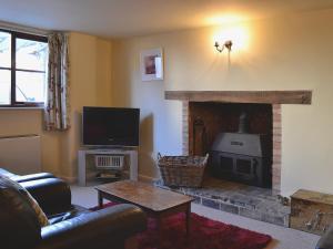 a living room with a fireplace and a television at Swallows Cottage in Tipton Saint John