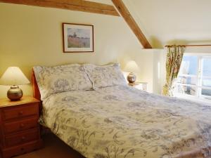 a bedroom with a bed and two lamps and a window at Swallows Cottage in Tipton Saint John