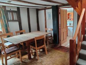 uma sala de jantar com uma mesa de madeira e cadeiras em Burnt House Cottage em Barking