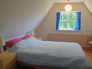 uma cama num quarto com uma janela em Burnt House Cottage em Barking