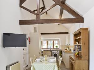 a kitchen with a table with chairs and a tv at Apple Cottage in Culmington