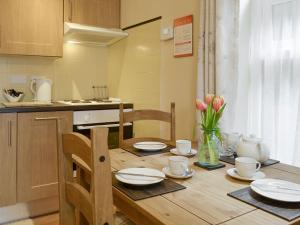 a kitchen with a wooden table with plates and cups at Eldin Hall Cottage 1 - Uk2483 in Cayton