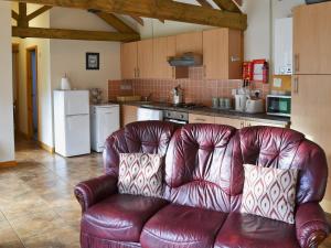 フランボローにあるPloughmans Cottageの茶色の革張りのソファーが備わるキッチン