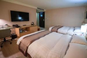 ein Hotelzimmer mit 2 Betten und einem Flachbild-TV in der Unterkunft Hotel Orchard Park - Taipei in Taipeh