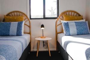 a room with two beds and a lamp on a table at Beachcomber Holiday Units in Lakes Entrance