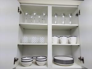 a white cupboard with plates and bowls and glasses at On the main street of HBC in Seoul