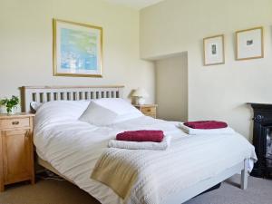 a bedroom with a white bed with red pillows on it at Gardenwell Cottage in Hawes