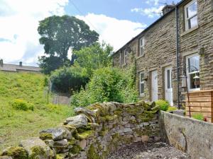 a stone wall in front of a stone house at Gardenwell Cottage in Hawes