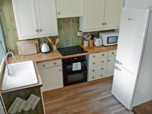 a kitchen with white cabinets and a refrigerator at Gardenwell Cottage in Hawes