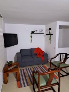 sala de estar con sofá azul y TV en Aparta Hotel Jardines de Guatape By Hope, en Guatapé