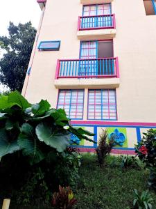 un edificio rosa con ventanas azules y una pintura en él en Aparta Hotel Jardines de Guatape By Hope, en Guatapé