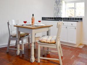 a kitchen with a table with two chairs and a bottle of wine at Sweet Briar Cottage in Holford