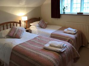 two beds in a hotel room with towels on them at Overwater Lodge in Bassenthwaite Lake