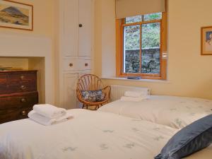 布雷思韋特的住宿－The Larches，一间卧室设有两张床、一把椅子和一个窗户。