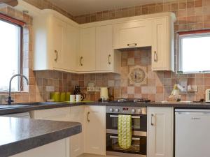 a kitchen with white cabinets and a stove top oven at Harwood Dale Cottage in Kendal