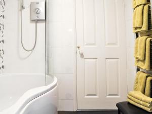a bathroom with a shower and a white door at Harwood Dale Cottage in Kendal