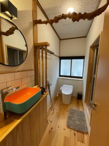 ein Badezimmer mit einer Badewanne, einem WC und einem Spiegel in der Unterkunft Yubaba House Downtown Apartments in Nozawa Onsen