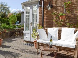 a patio with a couch and a table with a bottle of wine at The Studio in Cuckfield
