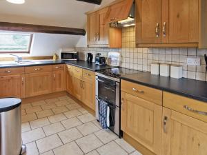 a kitchen with wooden cabinets and a stove top oven at Graianog Bach in Llanllyfni