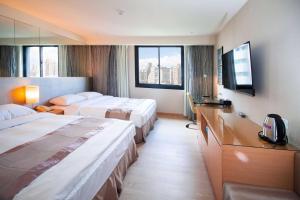 ein Hotelzimmer mit 2 Betten und einem TV in der Unterkunft Hotel Orchard Park - Taipei in Taipeh
