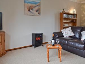 a living room with a leather couch and a wood stove at Kiln Cottage in Rye