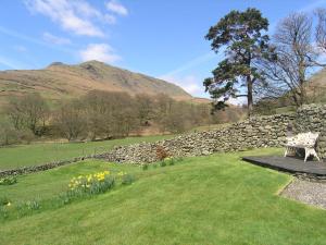 a bench sitting in a field next to a stone wall at 3 Townhead Cottages in Grasmere