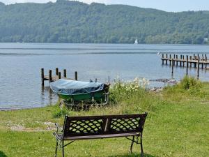 a bench sitting next to a boat on a lake at 3 Townhead Cottages in Grasmere