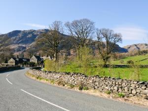 a road with a stone wall on the side of the road at 3 Townhead Cottages in Grasmere