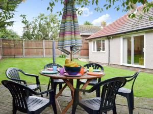 a table with a bowl of fruit and a umbrella at Hideaway Cottage in Kingsgate
