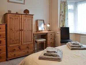 a bedroom with a bed and a dresser and a mirror at Hideaway Cottage in Kingsgate