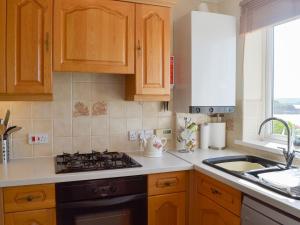 a kitchen with wooden cabinets and a stove top oven at Tarifa 7 in Bigbury on Sea
