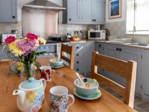 una cocina con una mesa de madera y un jarrón de flores en Greenridge, en Totland