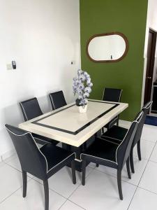 a dining room table with chairs and a vase of flowers at Hud-Hud Homestay 2 Gelang Patah in Gelang Patah
