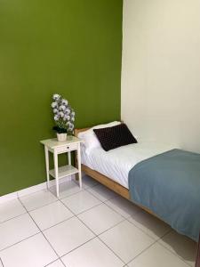 a green bedroom with a bed and a table with flowers at Hud-Hud Homestay 2 Gelang Patah in Gelang Patah