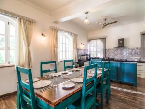 a dining room with a wooden table and blue chairs at Villa Beleza Infinita in Mapusa