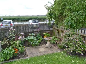 a garden with flowers and a fence and a bird bath at Reedcutters in Reedham