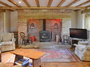 a living room with a brick fireplace and a tv at The Ashes in Middleton One Row