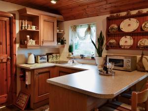 a kitchen with wooden cabinets and a counter top at Croiscrag Cottage in Aboyne