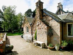 a stone house with a bench in front of it at Croiscrag Cottage in Aboyne