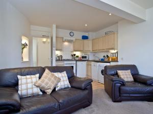een woonkamer met 2 leren banken en een keuken bij 2 Fishermans Loft in Brixham