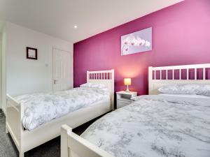 two beds in a bedroom with a purple wall at Graces Dairy in Wooler