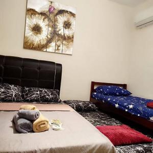 a bedroom with two beds and a bed with towels at Luxury UUC Homestay KKIP Telipok Kota Kinabalu in Kota Kinabalu
