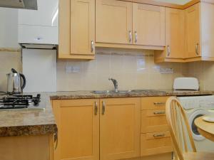 una cocina con armarios de madera y fregadero en Inglewood - 15288, en Keswick