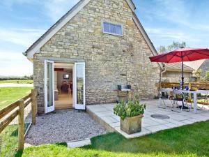 a stone cottage with a table and an umbrella at Antells Farm Barn in Sturminster Newton