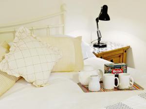 a tray of tea cups and coffee cups on a bed at The Coach House - Hw7782 in Llanarmon Dyffryn-Ceiriog